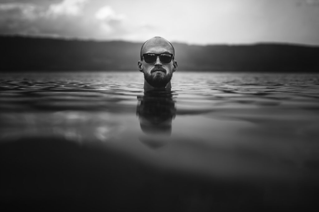 Man head above water in lake in rainy foggy day